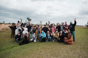 A diverse group of photographers posing together in a natural setting with cameras.